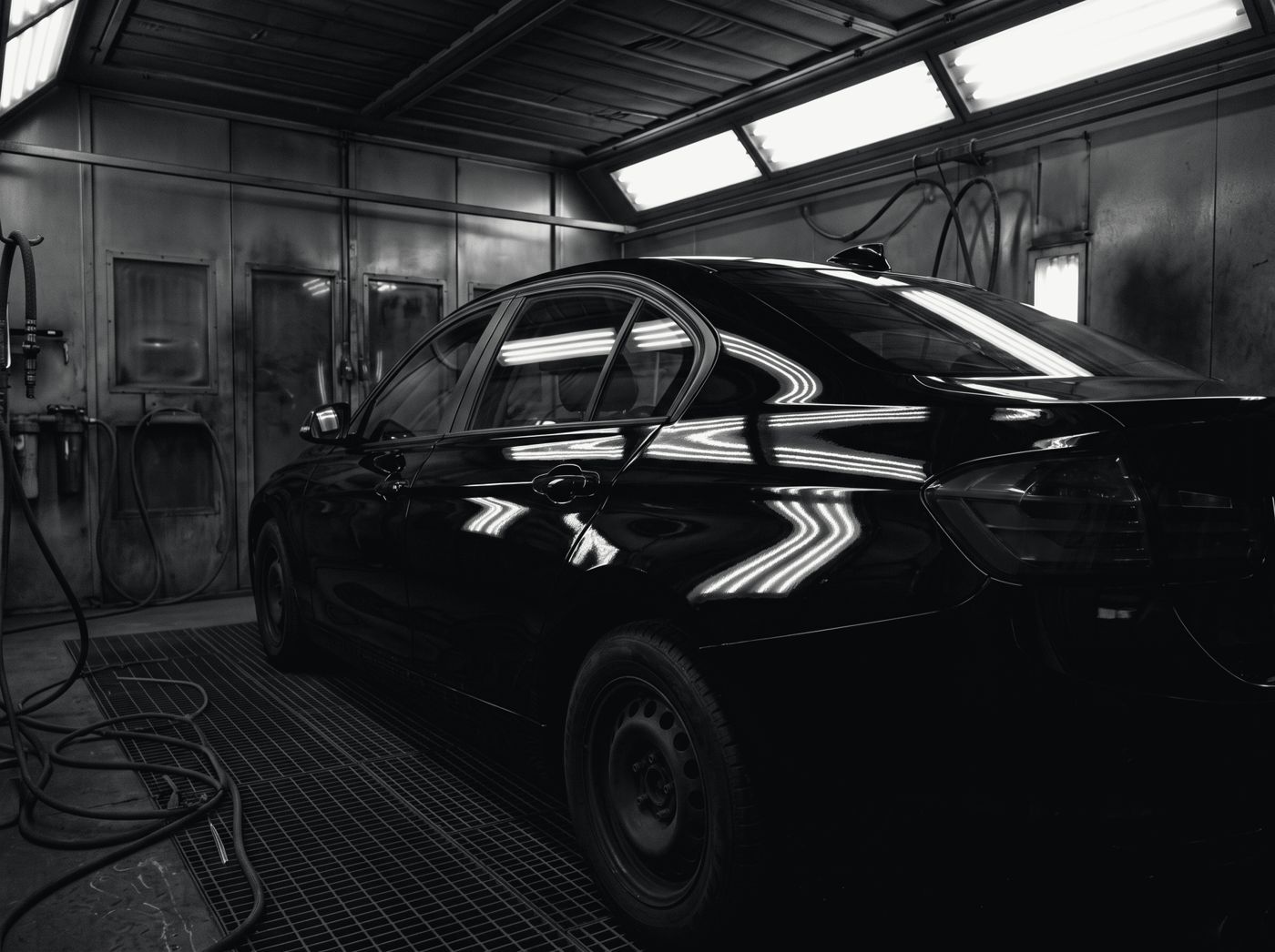 A dark saloon in a spray booth with freshly painted, high-gloss bodywork