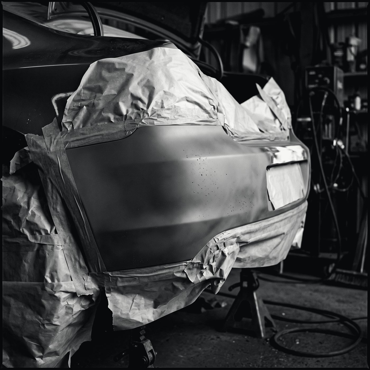 A bumper masked with paper and tape, sprayed in grey primer