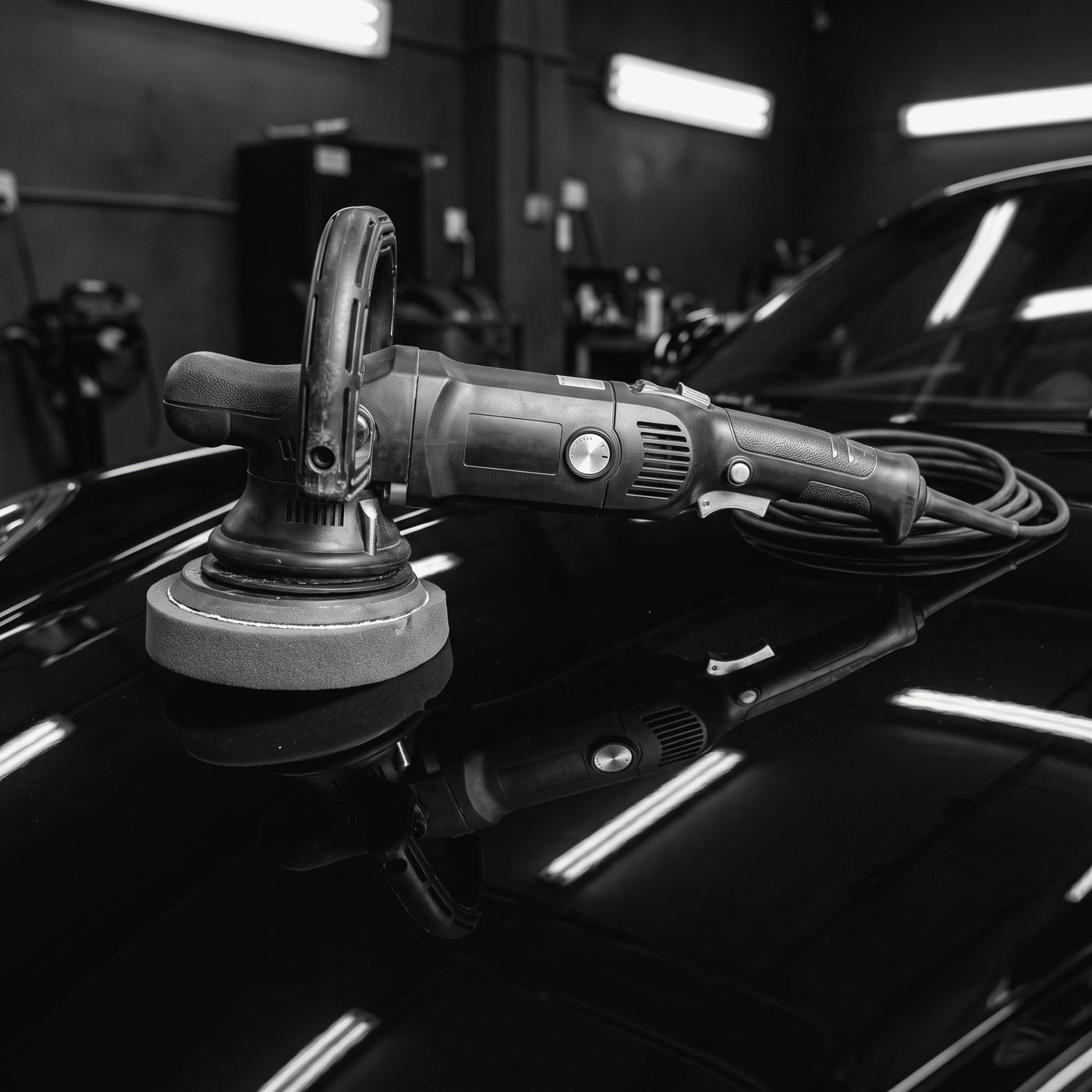 A machine polisher resting on a gleaming black bonnet