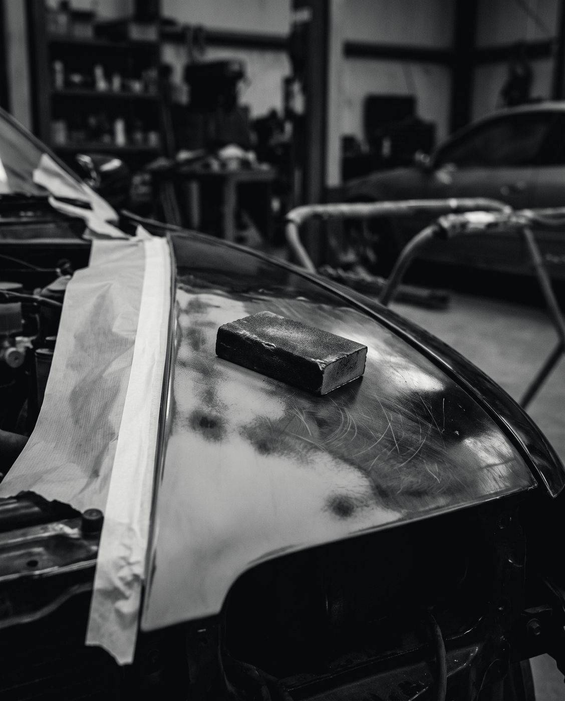 A car wing being prepared for paint, with primer feathered into the bodywork and masking along the edges